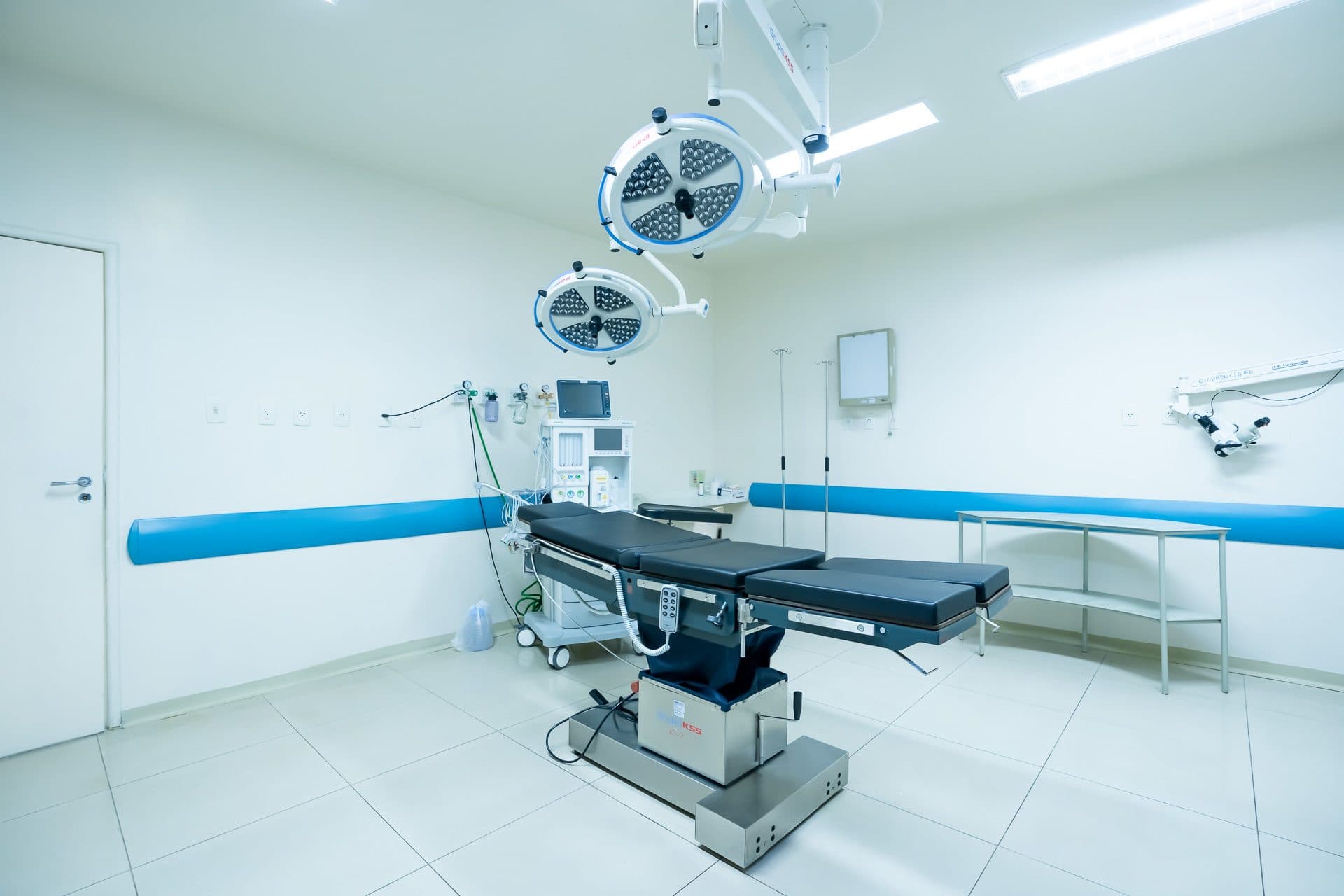 Sala cirúrgica com mesa, foco cirúrgico e equipamentos de anestesia